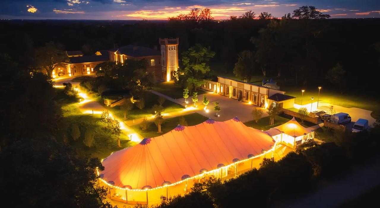 Château et chapiteau illuminés de l'Orangerie des Demoiselles au crépuscule